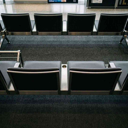 Interior of a modern airport terminal with black seats, waiting area