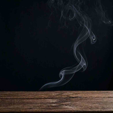 Smoke from the incense sticks on a wooden table on a black background