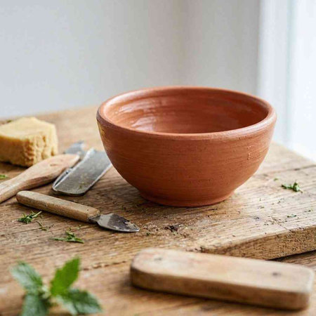 A clay pot with a knife and a shovel on a wooden table