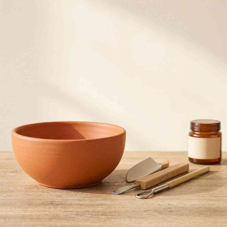 Empty clay bowl with wooden spatula on wooden table and copy space
