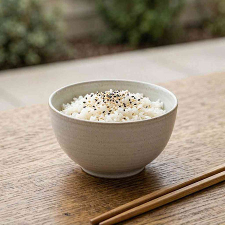 Bowl of rice with sesame seeds on a wooden table.