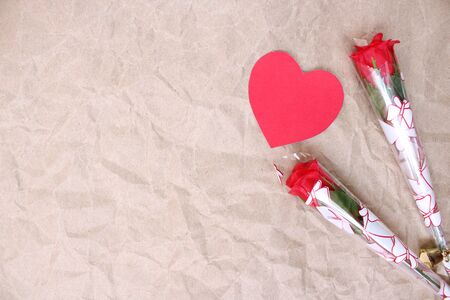 Red heart-shaped paper with fake roses on brown paper art on Valentines Dayの写真素材