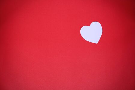 White heart-shaped paper on a red background with the concept Valentines Dayの写真素材