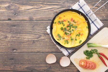 Omelette in a pan that is placed on a wooden background and free space for textの写真素材