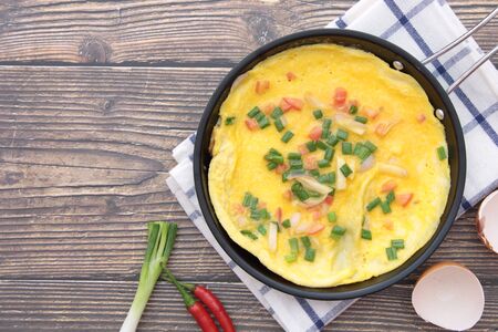 Omelette in a pan that is placed on a wooden background and free space for textの写真素材