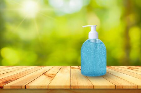 Alcohol wash hands, gel is on a wooden table with a backdrop of natural green bokeh.の写真素材
