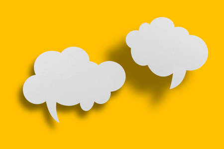 White paper in speech bubble shape set against yellow background.Communication bubbles.の写真素材