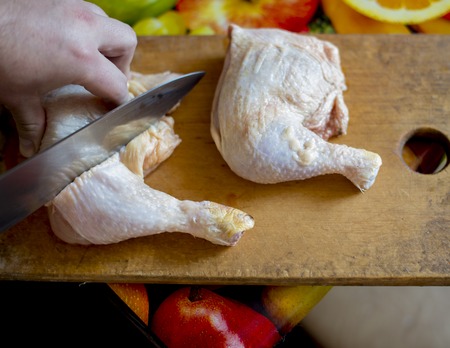 Cooking chicken thighs on the board with knife
