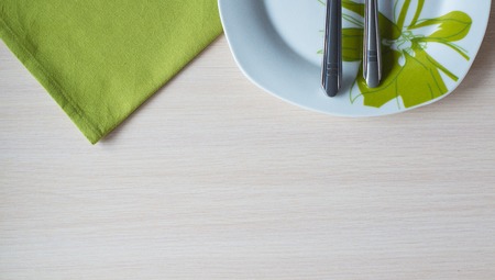 green napkin knife fork on a wooden table plateの写真素材
