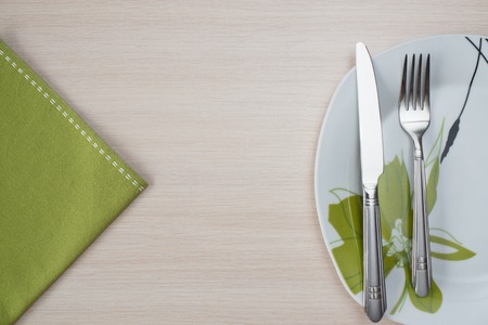 green napkin knife fork on a wooden table plateの写真素材