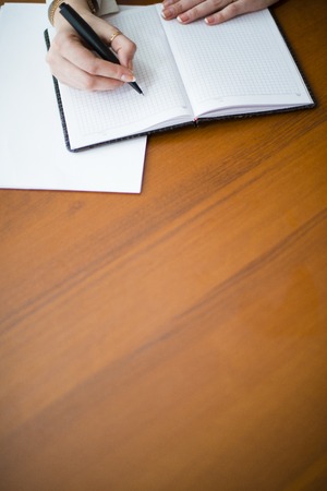 she writes pen on a pad on the tableの写真素材