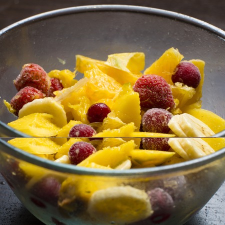 fruit salad in a glass bowl on a wooden surfaceの写真素材