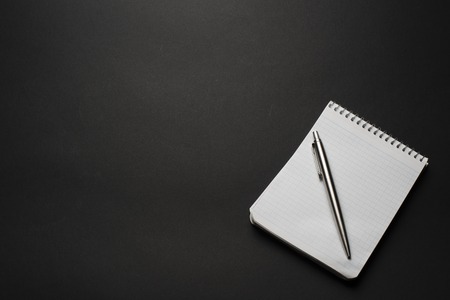 notebook and pen on a black table background