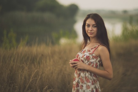 Lady with an apple standing in tall grassの写真素材