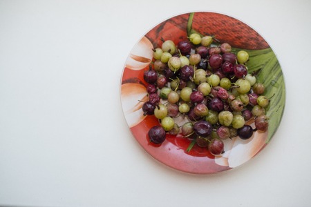 green and red gooseberries on a plateの写真素材
