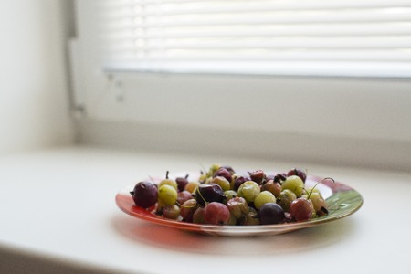 green and red gooseberries on a plateの写真素材