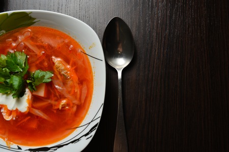 Red borsch with greens on a black table