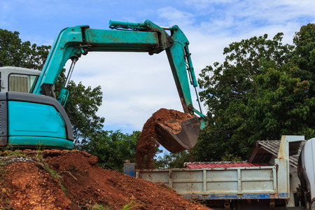 Industrial loader excavator moving earth and unloading on a dumper truckの写真素材