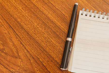 Blank notebook with pen and calculator on wooden table, business conceptの写真素材