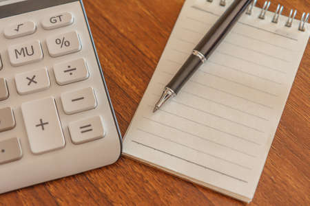 Blank notebook with pen and calculator on wooden table, business conceptの写真素材