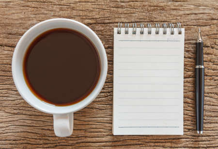 Blank notebook with pen and coffee on wooden table, business conceptの写真素材