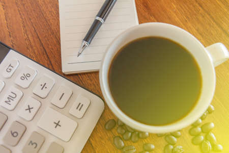 Blank notebook with pen,coffee and calculator on wooden table, business concepの写真素材