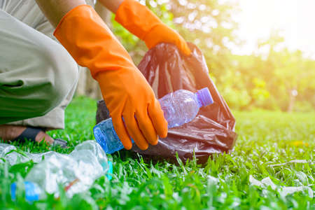 Volunteer man collecting trash.Garbage bottles picked up. Plastic and food waste concept. Clean planet Earth, collect garbage, save environment,save earth.の写真素材