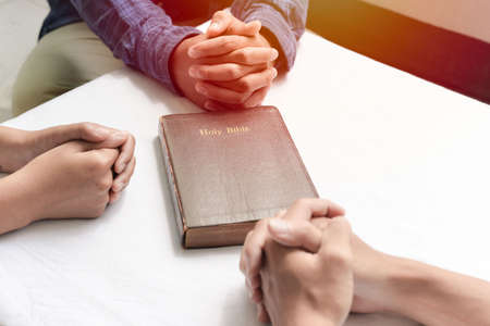 Christian groups sitting within the Church. Studying the word of God in churches. devotional or prayer meeting concept. Group of interlocked fingers praying togetherの写真素材