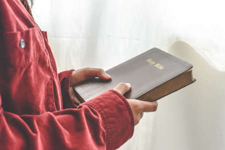 A woman is holding and hug the bible in the morning. Hands folded in prayer on a Holy Bible in church concept. worship and religion. copy spaceの写真素材