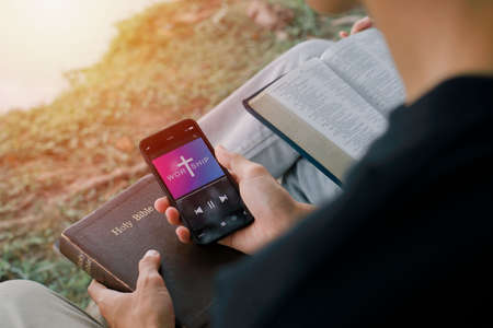 Two adults worship with smartphone at home. Progress Bar Loading with the text: Jesus on smartphone screen. Church online concept.の写真素材