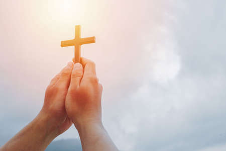 Silhouette off hands holding wooden cross on sunrise background. Christian, Christianity, Religion copy space.の写真素材