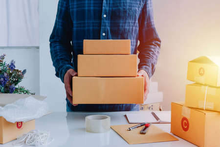 Closeup view of man online store small business owner seller entrepreneur packing package post shipping box preparing delivery parcel on table. entrepreneurial self employed business concept.の写真素材
