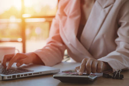 Young businesswoman using calculator working on laptop in her workstation.expenses finances taxes doing paperwork concept, close up viewの写真素材