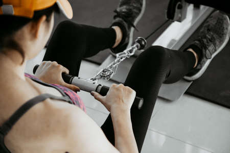 Young fit woman trains pectoral in a crossover exercise machine. Girl works out in modern gymの写真素材