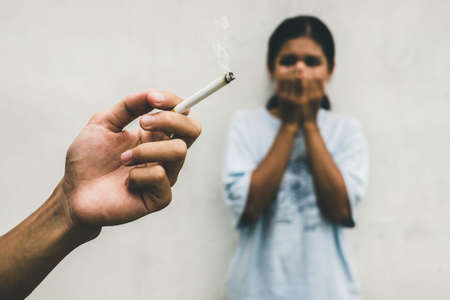 Man is smoking cigarette and woman is covering her face. Passive smoking and Healthcare or No tobacco day concept.の写真素材
