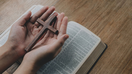 Woman with wooden cross in hands praying for blessing from god on old bible book. Spirtuality and religion, Religious conceptsの写真素材
