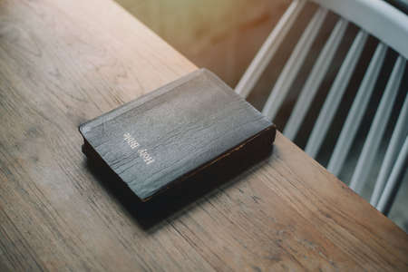 Holy bible on wooden table background with soft morning sun light. Christianity concept. Faith hope love concept.の写真素材