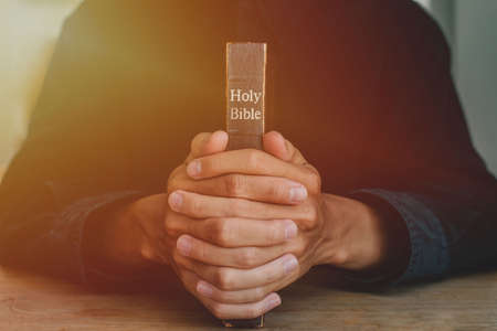 Hands of a man praying over a Bible represents faith and spirituality in everyday life. close up.の写真素材