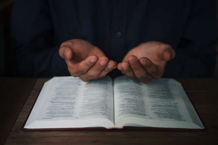 Man is reading and praying the scripture or holy bible on a wooden table with copy space. Religion, believe Concept.の写真素材