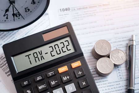Tax word and 2022 number on calculator. pen and coin on 1040 tax form. Business tax. The new year 2022 tax concept.の写真素材