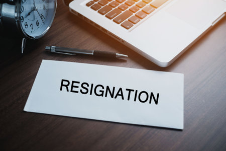 Resignation letter to executive on a wooden table with pen and laptop. Concept of termination of employment and resignation.の写真素材