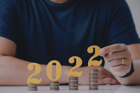 Man holding number 2022 with coin on white table. New year saving money and financial planning concept.の写真素材
