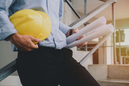 Close up of engineer man with construction helmet in hand. Working on stair at construction site. Building and architecture concept.の写真素材