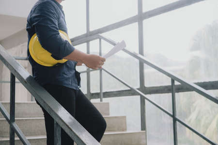 Close up of engineer man with construction helmet in hand. Working on stair at construction site. Building and architecture concept.の写真素材