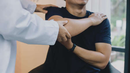 Physical therapists are checking patients elbows at the clinic office room. close up view of his hands.の写真素材