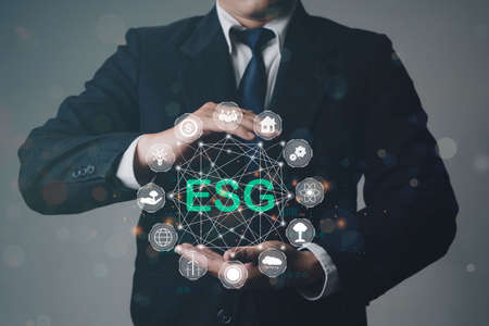 Close up of businessman hand holding to ESG icon concept for environmental, social, and governance...