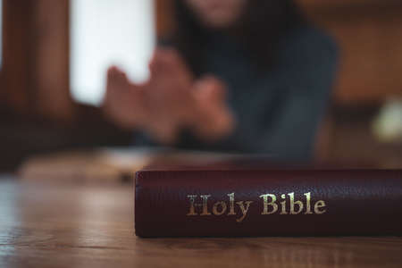 Close-up women christian read bible. Hands folded in prayer on a Holy Bible on wooden table.