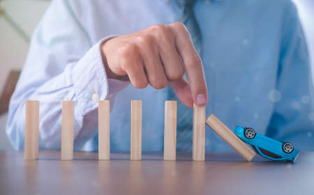 Car insurance Insurance officer hands stop the effects of car accident. Wooden domino. Business risk control Real estate concept.の写真素材