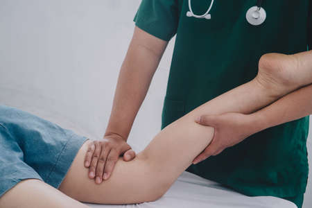 Treating thigh pain due to sitting for long periods of time Concept of physical rehabilitation. Consultation therapist with the treatment of treating injured thigh pain in modern clinics.の写真素材