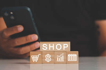 A man hand hold credit card to shopping online bill on wood block, Debit saving purchase buy on table background. People contactless pay money in restaurant, Person bank smart payment concept.の写真素材